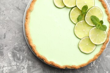 Tasty lime pie with fruit slices and mint leaves on grey textured table, top view © New Africa