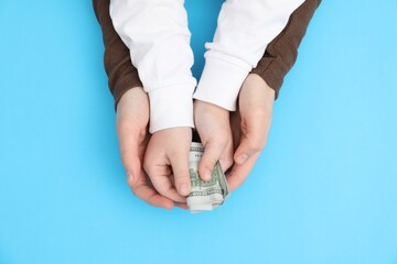 Alimony. Mother and daughter with dollar banknotes on light blue background, top view