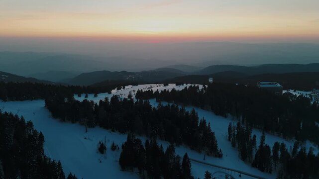 View of Kopaonik in Raška District during sunset over snow covered landscape and trees