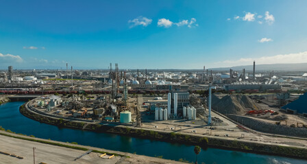 Aerial view of an extensive oil refinery with processing units and storage tanks in a coastal industrial area