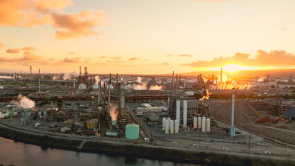Fototapeta premium Aerial view of an oil refinery complex with distillation towers and processing units during sunset