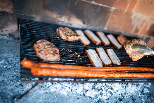 Grilling assorted meats and sausages over hot embers