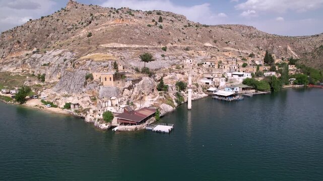 Experience a cinematic flight over the iconic half-submerged minaret of Savaşan Village in Halfeti. This footage highlights the haunting ruins and the turquoise depth of the Euphrates River.