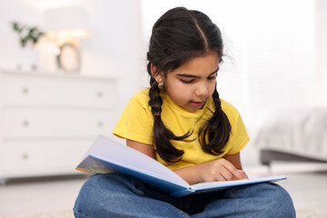 Fototapeta premium Cute little girl reading book at home