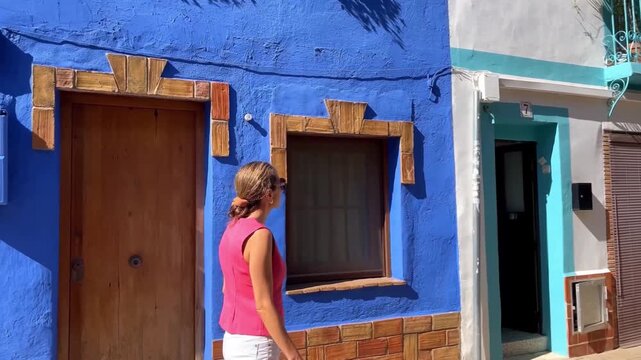Mujer caminando por calle de casas de colores Denia (slow motion)