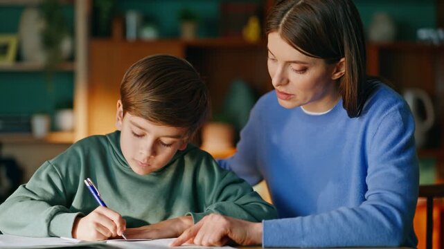 Mother supporting son study sitting together modern home workplace closeup.