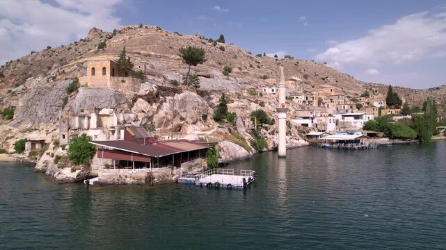 Experience a cinematic flight over the iconic half-submerged minaret of Savaşan Village in Halfeti. This footage highlights the haunting ruins and the turquoise depth of the Euphrates River.
