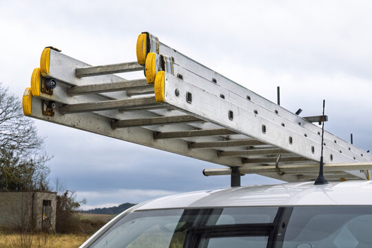 Aluminium extension ladder mounted on roof rack of contractor van