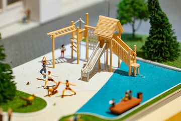 Naklejka premium Miniature humans practicing yoga and playing on a detailed scale model playground