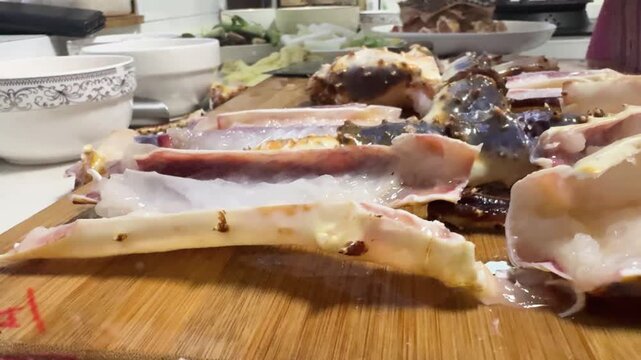 Preparing a live Shanghai hairy crab at home, with a cook cutting the crab using a large cleaver on a wooden cutting board to remove the meat from the hard shell before steaming in a kitchen setting.