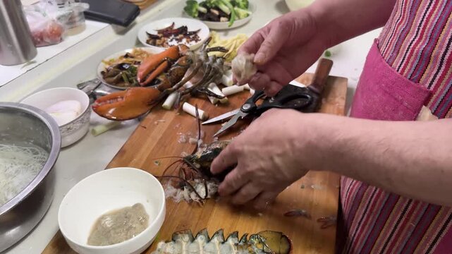 Preparing a live Shanghai hairy crab at home, with a cook cutting the crab using a large cleaver on a wooden cutting board to remove the meat from the hard shell before steaming in a kitchen setting.