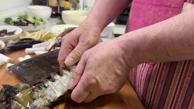 Preparing a live Shanghai hairy crab at home, with a cook cutting the crab using a large cleaver on a wooden cutting board to remove the meat from the hard shell before steaming in a kitchen setting.