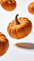 Several small orange pumpkins floating in the air against a white background
