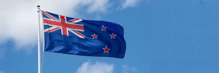 Majestic New Zealand flag waving gently in a clear blue sky, symbol of national pride and identity, vibrant colors
