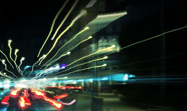 Abstract background. Colorful night street photography. Long exposure. Motion effect. Moving cars. Composition of light lines in perspective. Selective focus. Beautiful bokeh. Soft image.