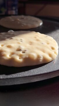 Close-up footage of pancake batter cooking in a hot pan, showing bubbles forming. Perfect for cooking tutorials, food preparation, and breakfast-related content.