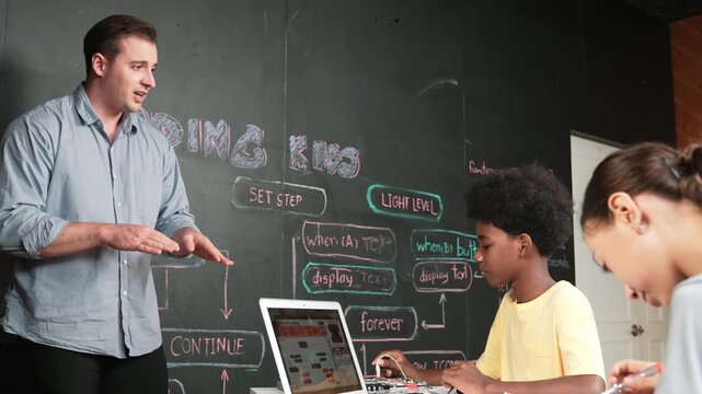Teacher teaching about coding system while diverse academic student fixing main board at table with laptop display programming prompt or engineering code at STEM technology classroom. Edification