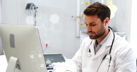 Reviewing doctor in white coat and stethoscope consulting records at clinic desk, with monitor © vectorfusionart