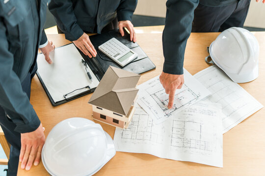 Businessmen having a meeting in front of a house model and blueprints