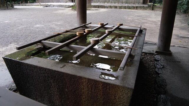 Traditional temizuya purification basin at a Japanese Shinto shrine, where visitors use wooden ladles to rinse their hands before entering the sacred grounds. Ritual practice and spiritual tradition.
