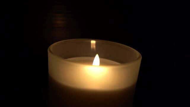 Close up of a lighter lighting a candle in a glass jar against