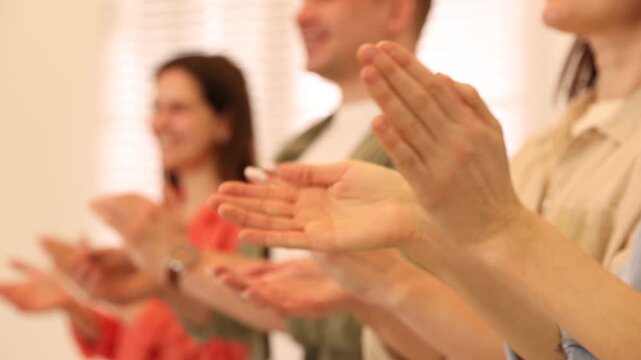 Group of people clapping hands indoors, selective focus