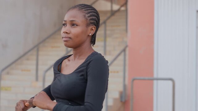 Black woman dancing on outdoor stairs with braided hair, black top and expressive gestures urban rehearsal vibe, confident motion, candid portrait, fitness energy and choreography practice