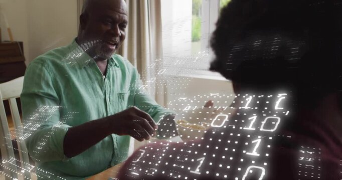 Senior man reaching to pass bowl at dining table, technology binary grid overlaying family meal