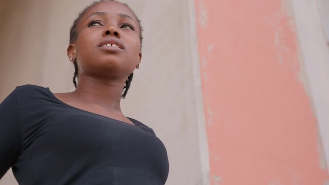 Urban dancer practicing graceful movements. Female performer warming up on steps with artistic intent. Woman with braided hair dances on pink stairs showcasing elegant motion and concentration