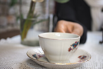 Fototapeta premium Person serves tea in porcelain cup on a small plate