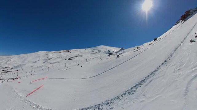 4K Cinematic drone footage of the Veleta peak and snowy slopes at Sierra Nevada Ski Resort, Spain, featuring panoramic mountain views under a bright sunny sky.