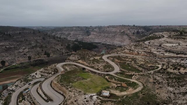 4K Cinematic drone shot of a winding mountain road along the Jucar River canyon, Spain, featuring a car driving through the spectacular limestone gorge