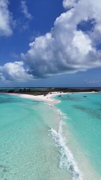 Vertical aerial zoom in of a couple holding hands walking the Paso de Mois&eacute;s sandbar at Cayo de Agua, Los Roques Archipelago, Venezuela, romantic tropical Caribbean island beach