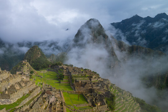 Morning sunny blue sky low clouds fog Huayna Machu Picchu Historic Sanctuary Temple rainy season Inca citadel Eastern Cordillera of southern Peru Incan citadel Peruvian Andes Mountains landscape pano