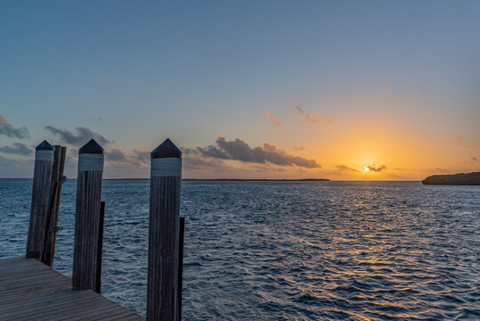 Orange sunrise over boat dock and calm tropical ocean
