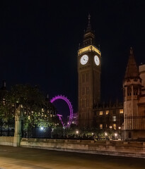 Fototapeta premium Big Ben clock tower seen from behind iron fencing at night. The layered view adds depth to London city landmark imagery.