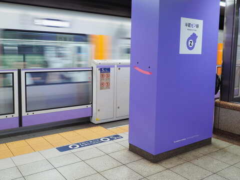 TOKYO, JAPAN - March 5, 2026: Train leaving a platform in Hanzomon Metro Station with logo featuring Pokemon Ditto on column during a collaboration between Pokemon and the Hanzomon Line.