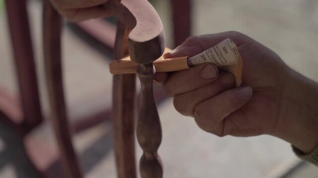 Close up of hand sanding wooden chair detail