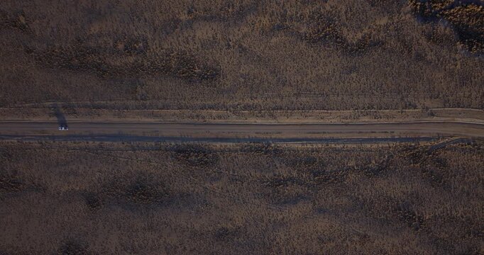 Close aerial of Highway 93 cutting across dry Idaho basin beneath mountain range