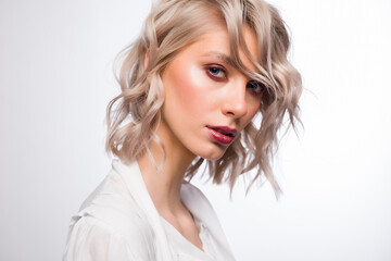 Naklejka premium A charming woman with perfect skin on a white background. The concept of beauty and skin care. She is wearing a snow-white blouse that is open.