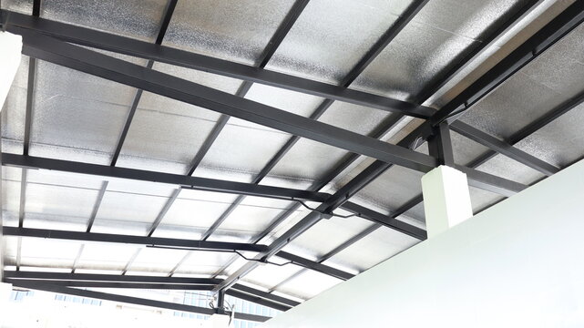 Steel roof structure. Metal roof structure on partial central pillars of a building covered with PE or PU insulation panels, in bottom view with selective focus.
