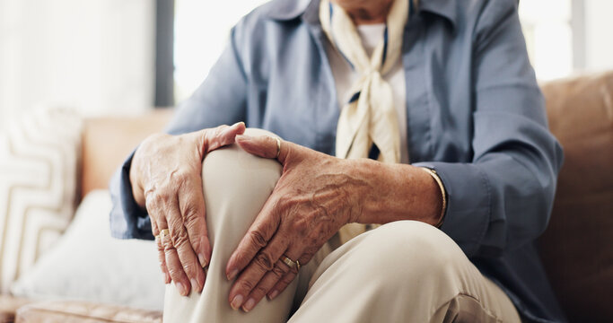 Hands, knee pain and injury in sofa in retirement home with fatigue, arthritis or muscle sprain in lounge. Elderly person, joint ache and fibromyalgia for inflammation, strain or tension at house