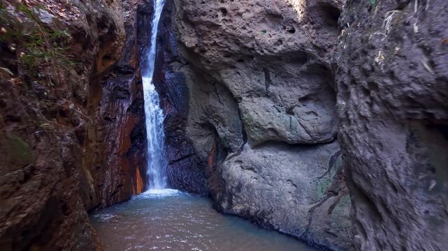 Drone video showing Pam Bok Waterfall in lush, rocky gorge near Pai, Thailand. Captures serene, natural atmosphere and rugged landscape from an overhead perspective.