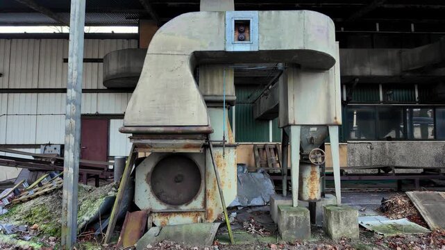 Old industrial installation and decayed machinery in an abandoned factory, rusty ventilation systems in a production hall, urbex atmosphere and forgotten industrial heritage, raw detail.