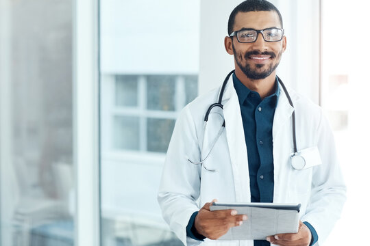 Doctor, man and tablet with smile at hospital with medical career, portrait and glasses in hallway. Person, tech and healthcare professional for services, window and confidence at clinic in Brazil