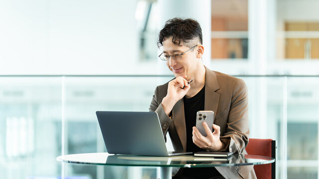 スマートフォンとノートパソコンを使う男性ビジネスパーソン, Businessman using a smartphone and laptop