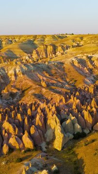 Vertical video. Goreme, Nevsehir, Turkey. Abstract natural art of Devrent Valley with surreal stone formations and mineral colors in evening illumination.. Aerial View, MasterShots, Circle (Far). Ric