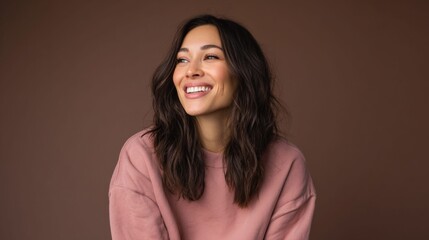 Fototapeta premium Smiling woman with long dark hair looking away, wearing a pink sweater