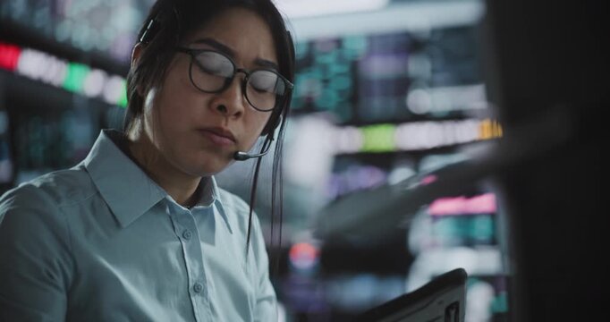 Stressed Female Broker Communicating Crisis Updates on Mobile, Backed By Multi Screen and Tablet Analytics. Constant Data Verification, High Pressure Decision Making in Fast Paced Digital Exchange.