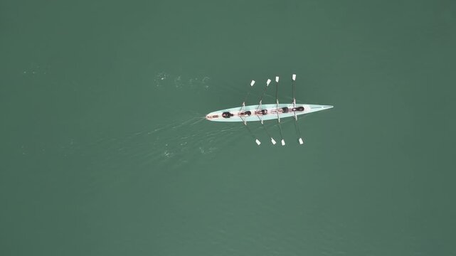 Eight Rowers In Narrow Shell, Synchronized Strokes Drive Steady Wake, Coxswain Sets Cadence While Athletes